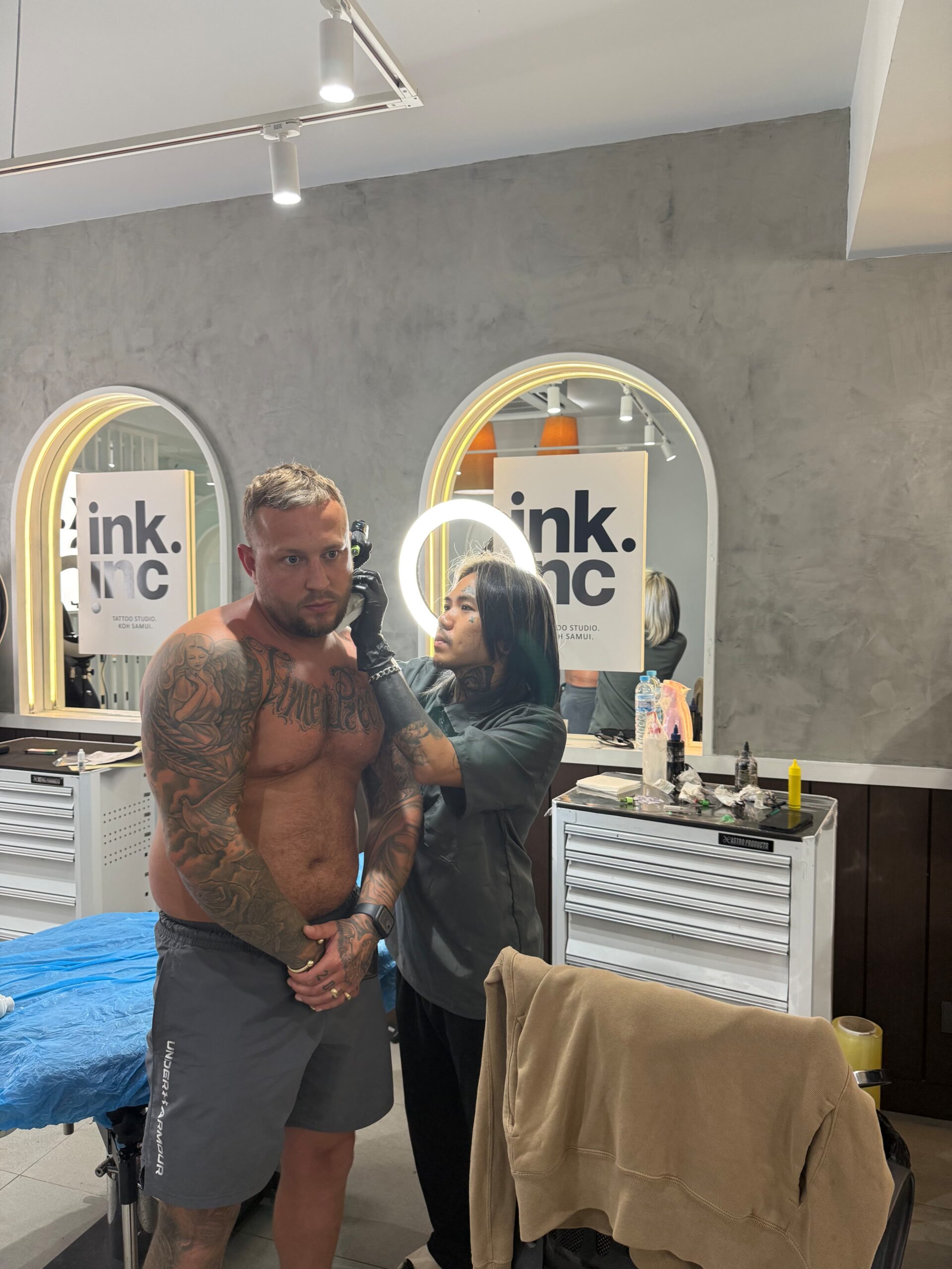 Tattoo artist applying a large stencil to a client's back.